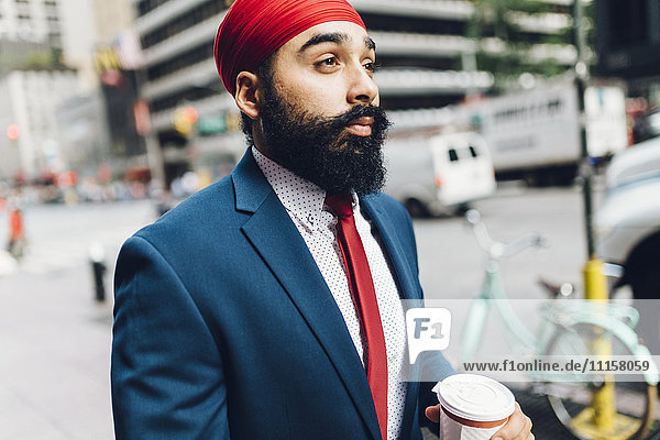 Indischer Geschäftsmann  der in Manhattan spazieren geht und Kaffee trinkt.