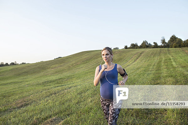 Schwangere Frau beim Joggen im Feld