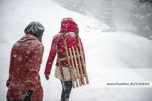 Two young women with sledges in heavy snowfall
