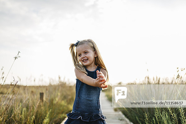 Fröhliches kleines Mädchen auf einer Promenade in der Natur stehend
