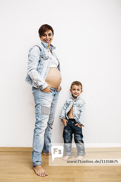 Schwangere Mutter und kleiner Sohn stehend mit Händen in den Taschen
