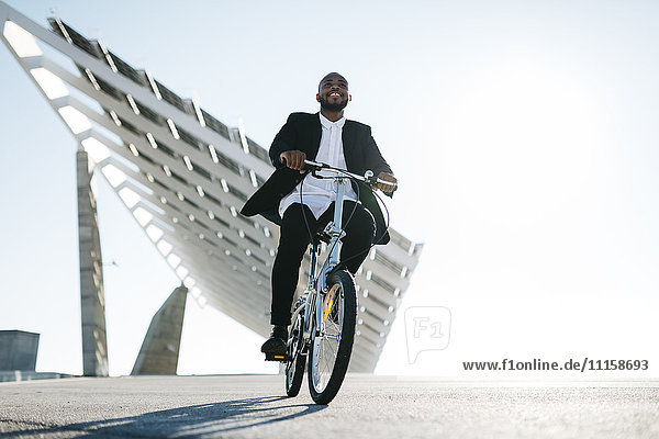 Geschäftsmann auf dem Fahrrad an Solarpaneelen