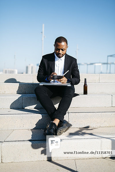 Geschäftsmann auf der Treppe sitzend mit Bierflasche  Notebook und Laptop