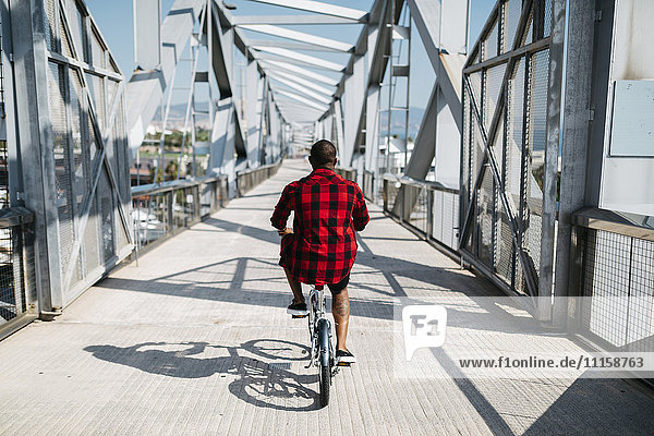 Mann fährt Fahrrad auf einer Brücke