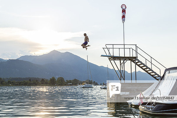 Austria  Sankt Wolfgang  man jumping from platform into lake