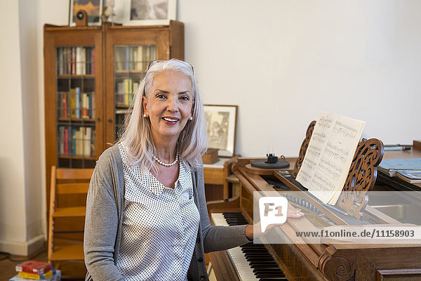 Porträt einer lächelnden Frau mit Klavier zu Hause