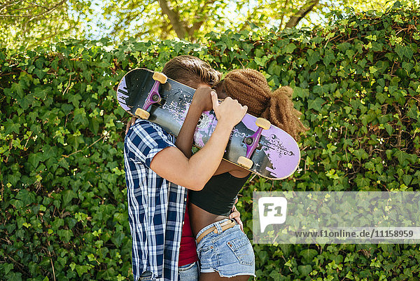 Pärchenküssen hinter einem Skateboard