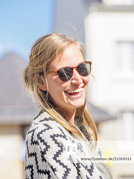 Porträt einer glücklichen jungen Frau mit Sonnenbrille