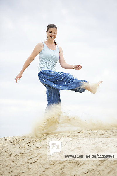 Lächelnde junge Frau tritt in den Sand