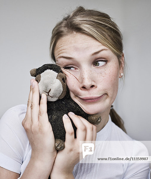 Young woman making a funny face holding cuddly toy