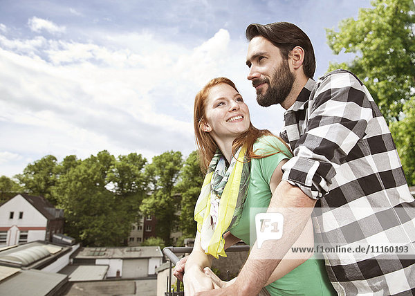 Smiling young couple on balcony in the city