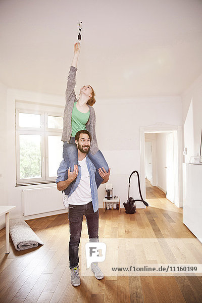 Young couple exchanging a light bulb in their new apartment together