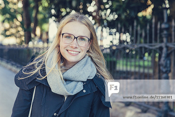 Porträt einer lächelnden jungen Frau mit Brille und Schal