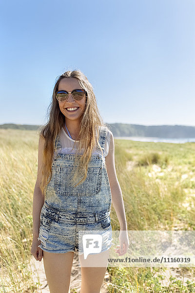 Portrait of smiling teenage girl wearing dungarees on the beach