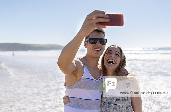 Young couple taking selfies on the beach