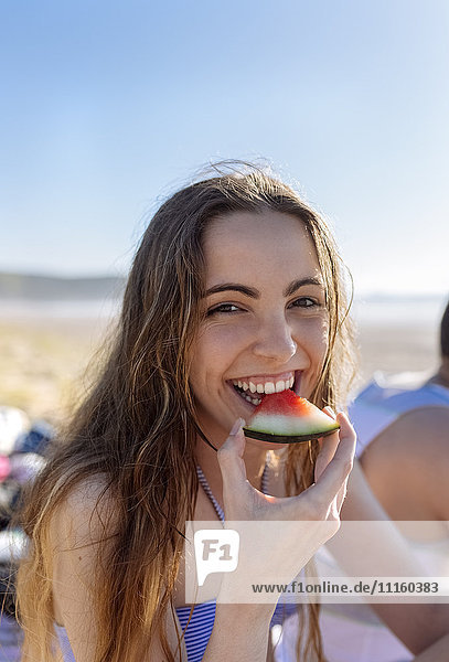 Porträt eines lächelnden Mädchens  das Wassermelone am Strand isst.