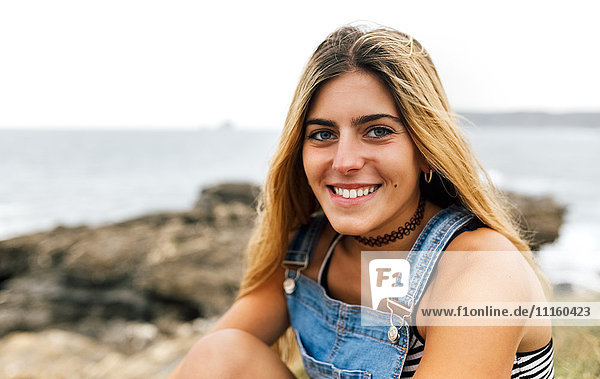 Portrait of smiling teenage girl sitting at the coast