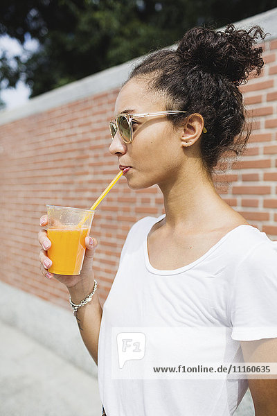 Young woman drinking an orange juice outdoors
