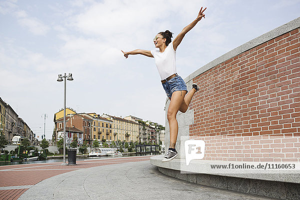 Überschwängliche junge Frau beim Springen im Freien
