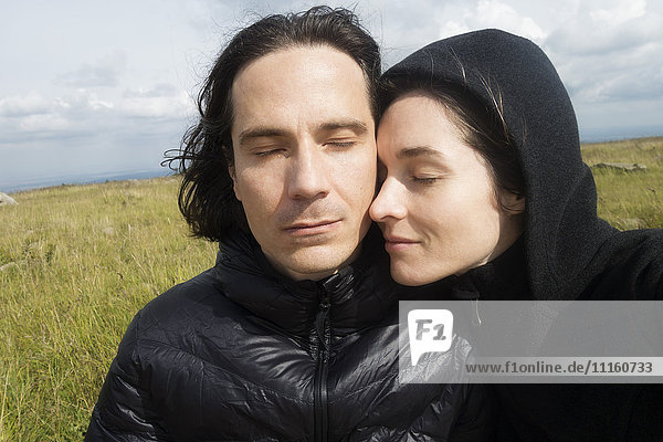 Paar in schwarz gekleidet mit geschlossenen Augen und Kopf an Kopf
