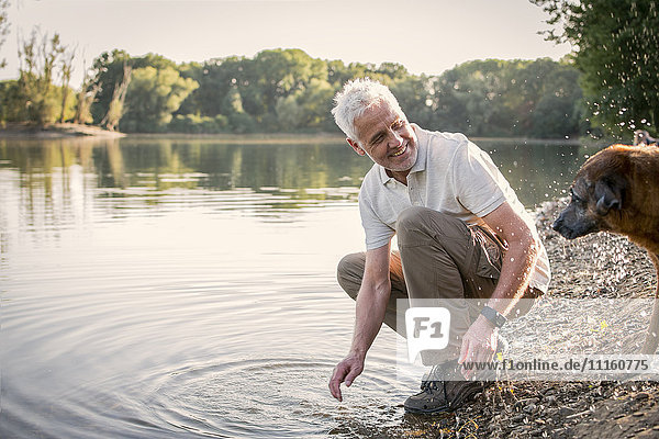 Senior man playing with dog at a lake