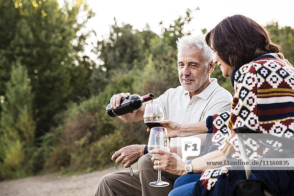 Senior man pouring red wine into glass for his wife