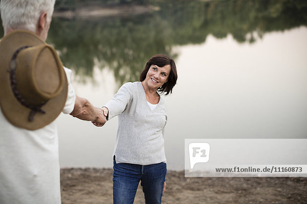 Glückliches Seniorenpaar Hand in Hand an einem See