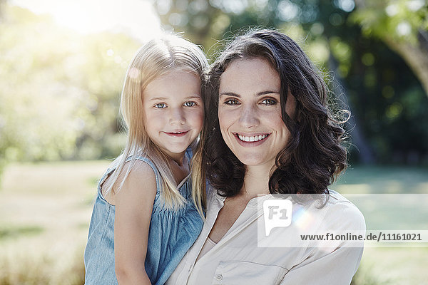Portrait of smiling mother with daughter in garden