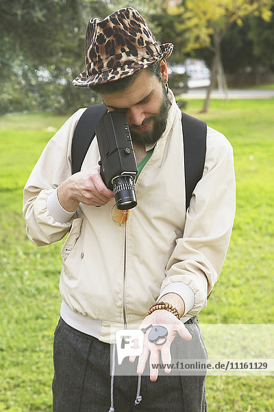 Man recording heart-shaped love lock on his hand with vintage video camera