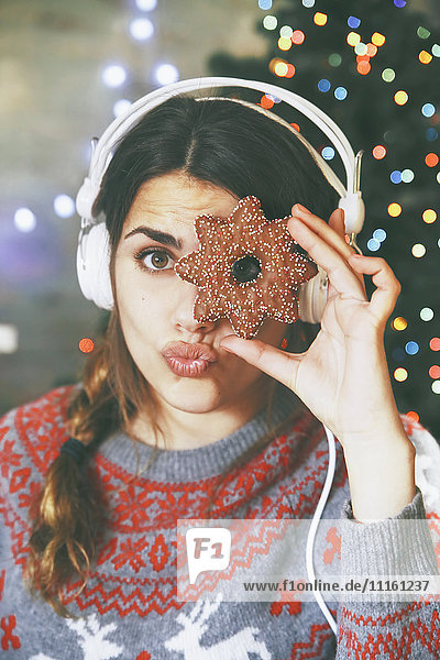 Frau mit Kopfhörer  die durch ein Weihnachtsgebäck schaut.
