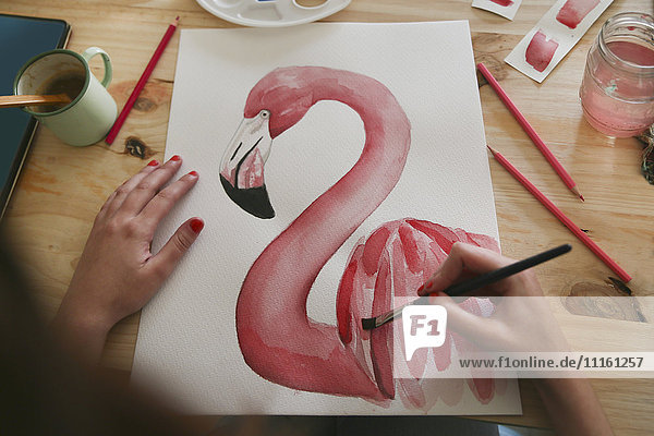 Damenhandmalerei Aquarell eines Flamingos auf dem Schreibtisch im Atelier