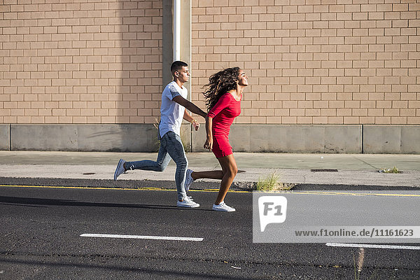 Teenager-Paar läuft Hand in Hand auf einer Straße