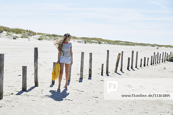 Junge Frau an Holzstangen am Strand