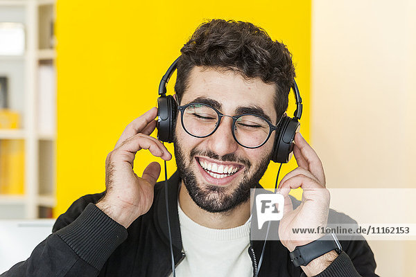 Porträt eines lachenden Mannes mit Musikhören über Kopfhörer