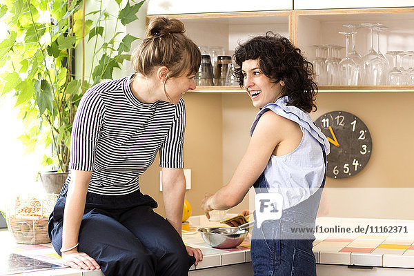 Zwei lachende Frauen zusammen in der Küche