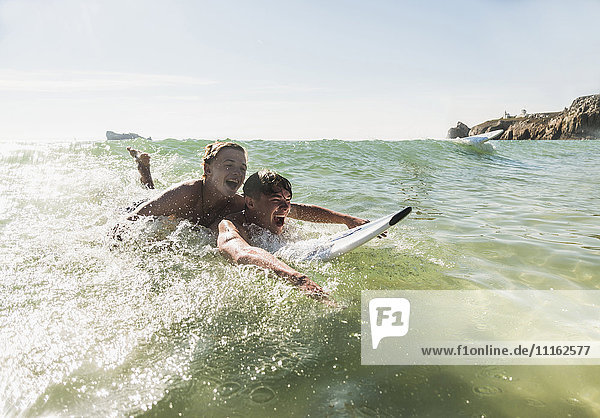 Zwei Freunde haben Spaß auf dem Surfbrett im Meer