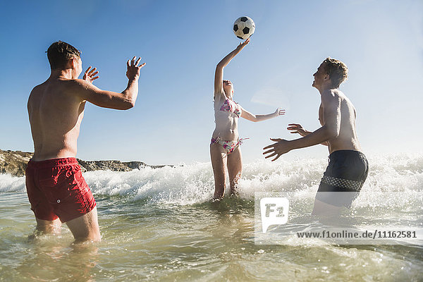Friends playing with a ball in the sea