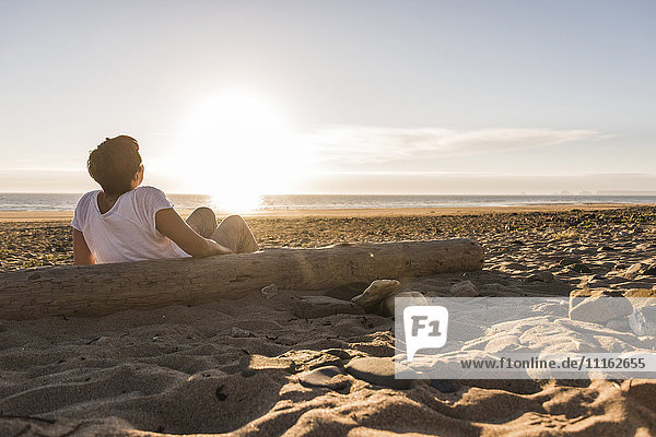 Frankreich  Bretagne  Halbinsel Crozon  Frau bei Sonnenuntergang am Strand sitzend