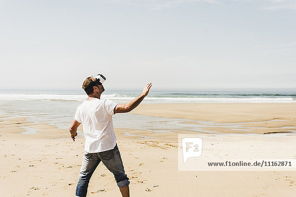 Erwachsener Mann am Strand stehend mit VR-Brille