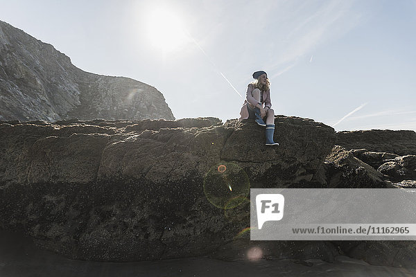 Frankreich  Halbinsel Crozon  Teenagermädchen auf Felsen am Strand sitzend