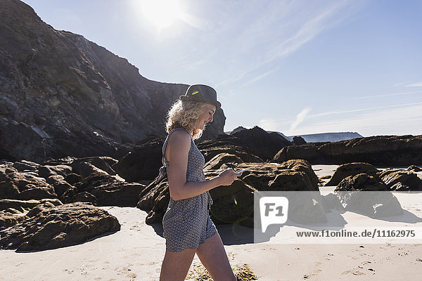 France  Crozon peninsula  teenage girl with cell phone walking on the beach