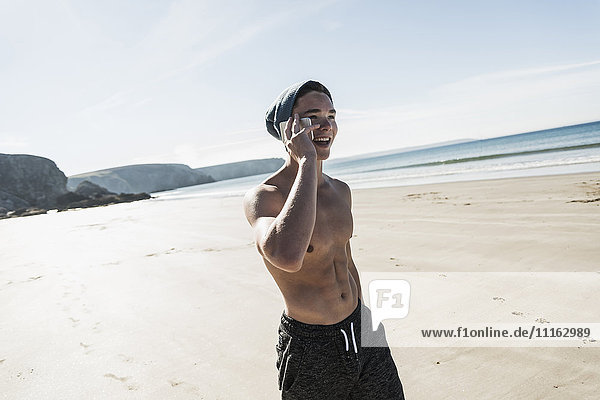 France  Crozon peninsula  happy young man on cell phone on the beach
