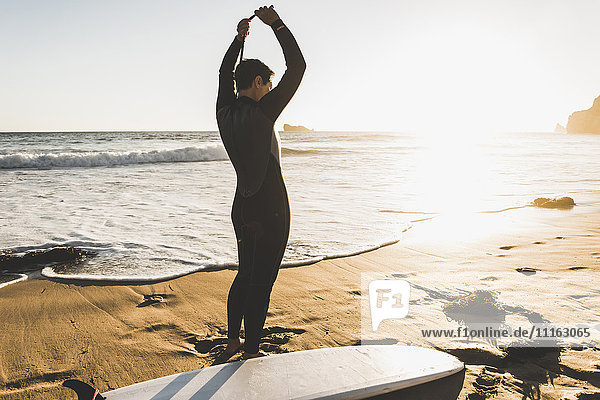 Frankreich  Bretagne  Halbinsel Crozon  Frau am Strand stehend bei Sonnenuntergang mit Surfbrett