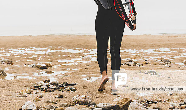Frankreich  Bretagne  Halbinsel Crozon  Frau mit Surfbrett am Strand unterwegs