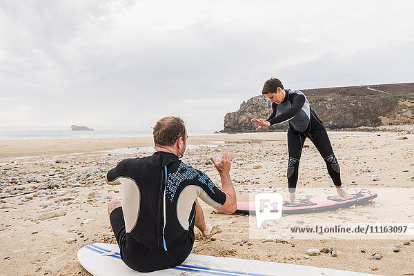 France  Bretagne  Crozon peninsula  man teaching woman surfing on beach
