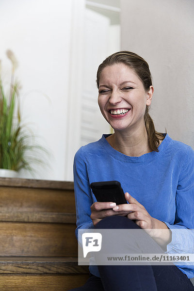 Lachende junge Frau mit Smartphone