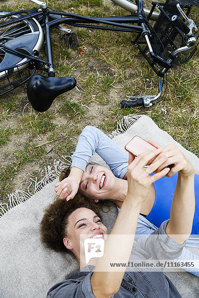 Zwei glückliche junge Frauen  die einen Selfie auf die Decke nehmen.