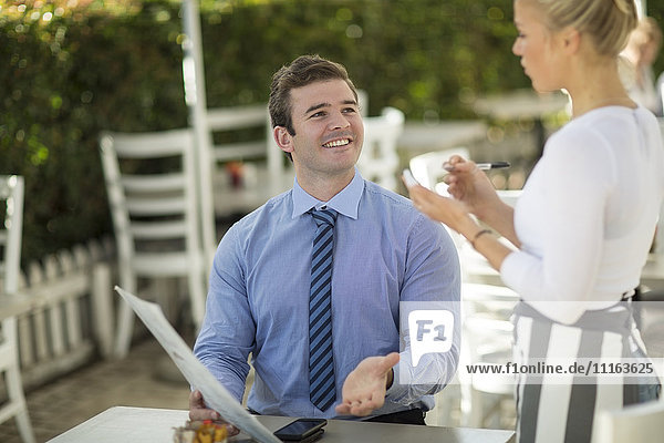 Portrait of smiling businessman ordering at outside restaurant