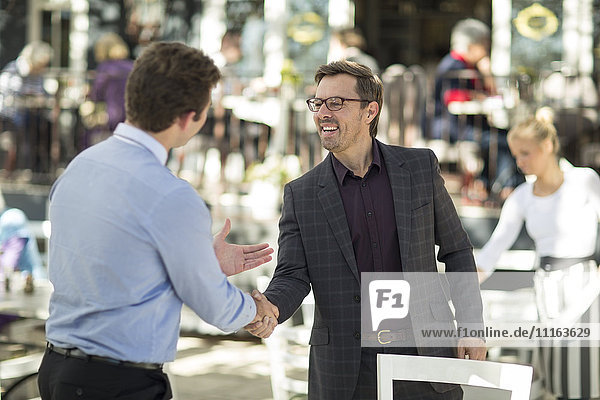 Two businessmen shaking hands at outside restaurant
