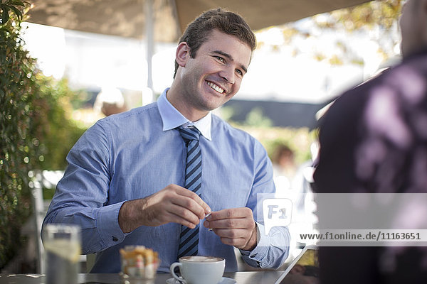 Portrait of smiling businessman drinking coffee with business partner